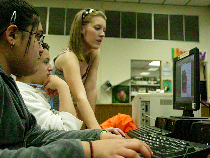 Western Washington University student Kaelee Berg, right, helps Shuksan Middle School students Sumeet Panwar and David Trejo create community action flyers for their group Operation Change during a mentoring session at the middle school this past year. Ph