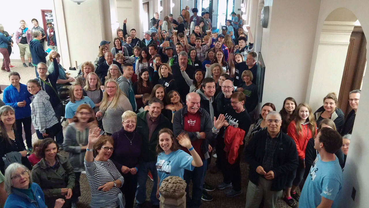 a crowd of people on the first floor of Wilson Library face the camera and wave