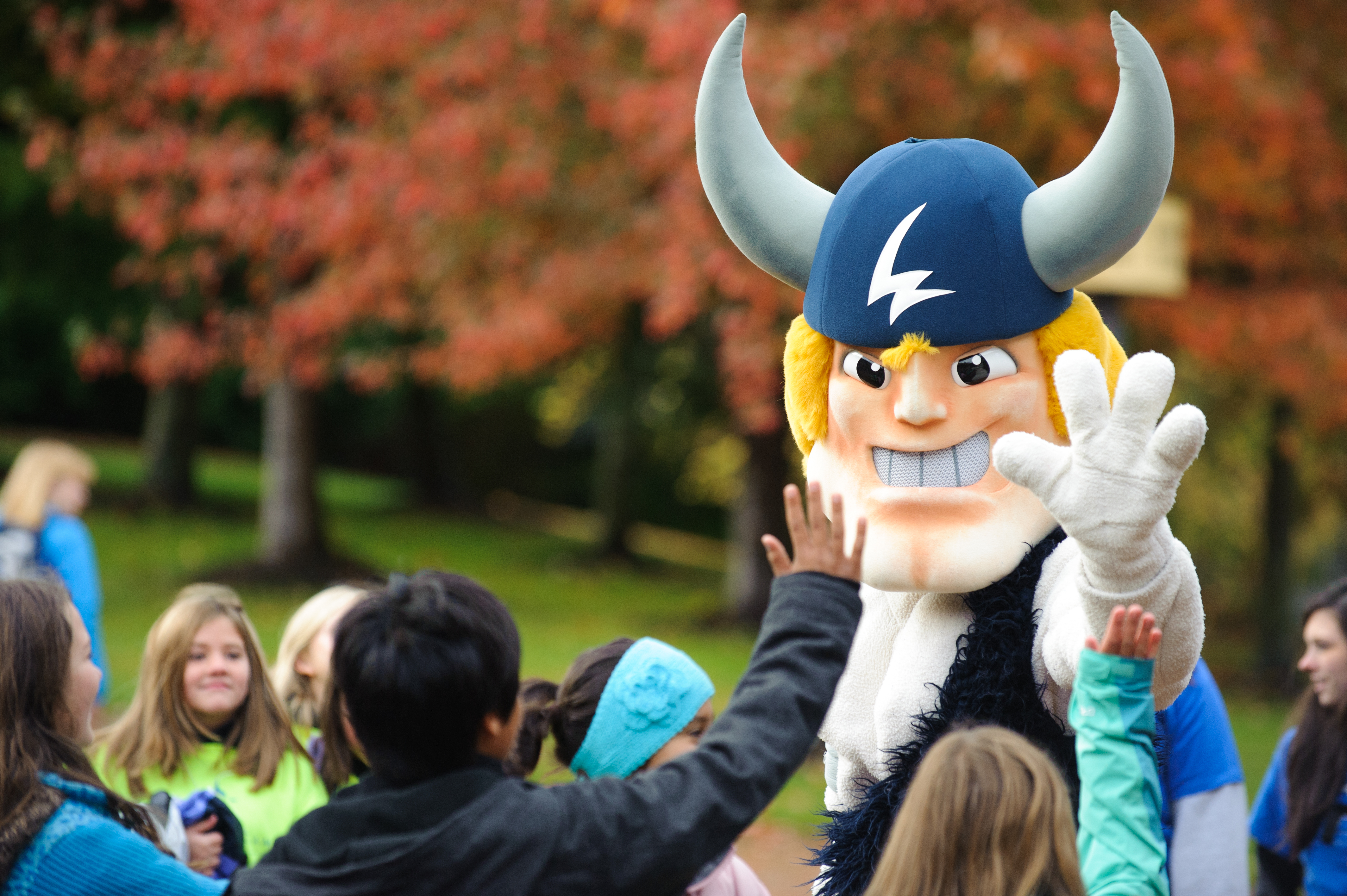 Someone in a Viking mascot costume high-fives a group of kids