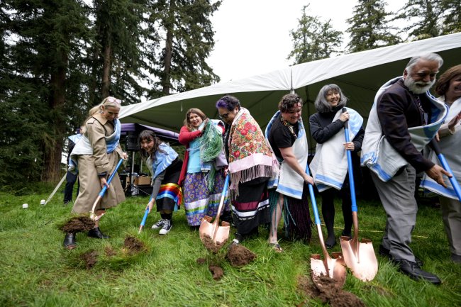 Attendees plunge golden shovels into the ground at the longhouse ceremony.