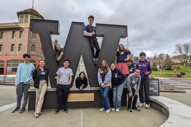 Several students pose on and around a large metal 'W' at University of Washington Tacoma