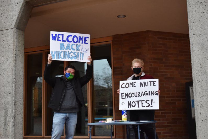 Zach Welsh, left, a recent Western alumnus, and Jonathan Martens, an International Business major from Ferndale, stand outside Red Square holding up signs welcoming back students and encouraging them to write notes for others.
