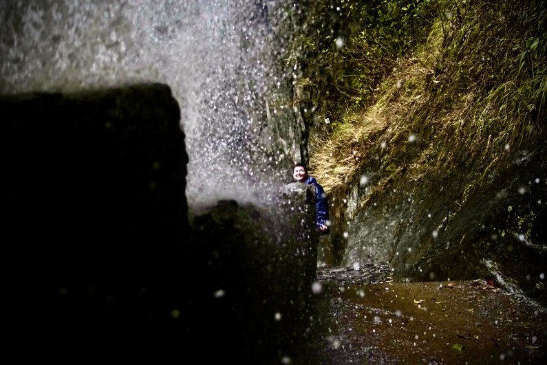 The Pailon del Diablo waterfall splashes on a walkway as a student looks on in awe.
