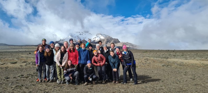 The group gathers on flat ground with snow-capped Chimborazo in the background as the clouds clear up.