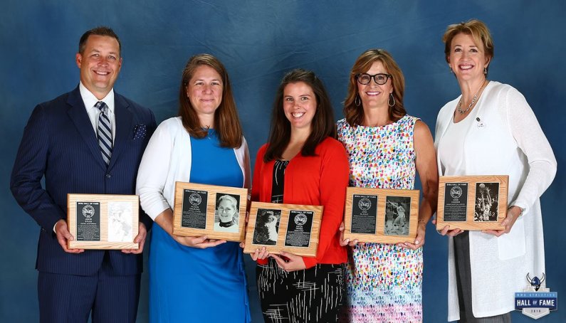 Five people stand holding plaques for their WWU Athletic Hall of Fame recognition