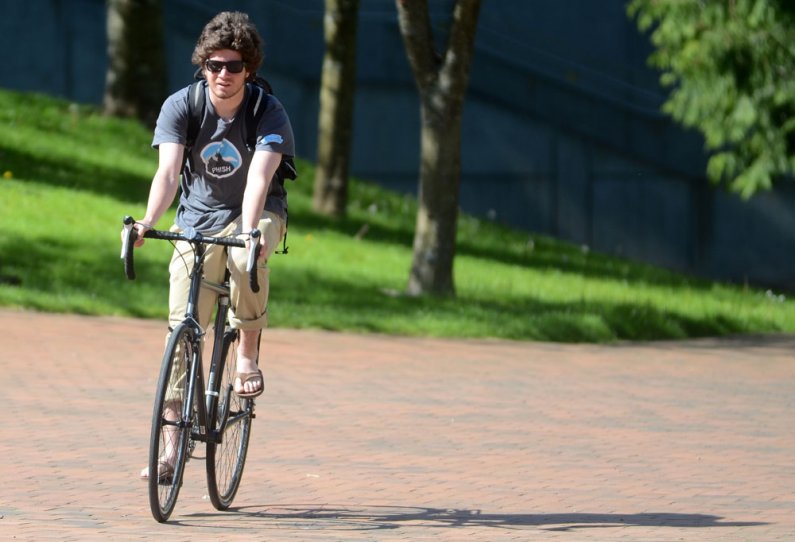 Western student Jerry Mark rides his bike past Carver Gym on Bike to School and Work day Friday, May 20."I actually didn't know today was special," Mark says. "I normally ride my bike to school." Photo by Daniel Berman | University Communications intern