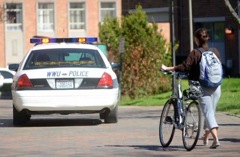 A WWU student walks her bike past College Hall as a University Police officer drives by on Bike to School and Work day Friday, May 20. Photo by Daniel Berman | University Communications intern