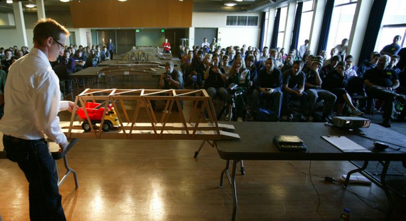 A crowd of roughly 100 Sehome High School students and about 60 WWU students watch as associate professor Jason Morris tests one of the cardboard bridges in a competition in the Viking Union Multipurpose Room on Oct. 19, 2010. Photo by Matthew Anderson | 