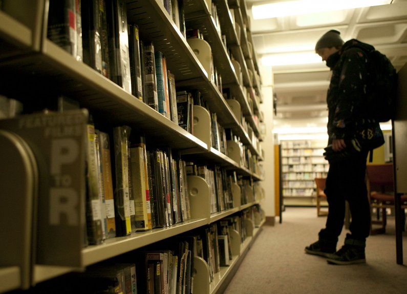 A Western Washington University browses the shelves of feature films in Wilson Library, looking for something to check out. Photo by Matthew Anderson | WWU