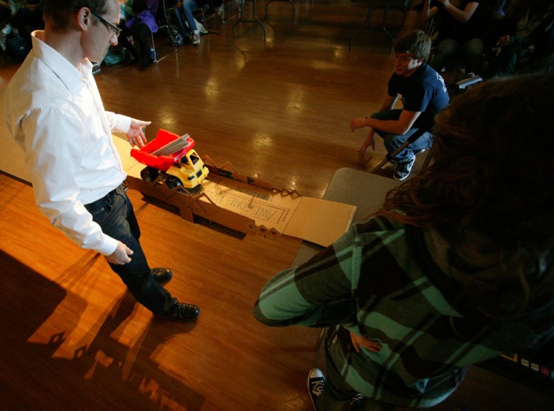 Students involved in a bridge-building contest on the WWU campus watch as associate professor Jason Morris tests their bridge in the Viking Union Multipurpose Room on Oct. 19, 2010. Photo by Matthew Anderson | University Communications
