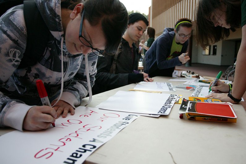 During a rally on campus Friday, Feb. 5, Western Washington University student Kristin Williamson, left, creates a sign to be used in a rally planned for Feb. 15 in Olympia. Photo by Matthew Anderson | WWU