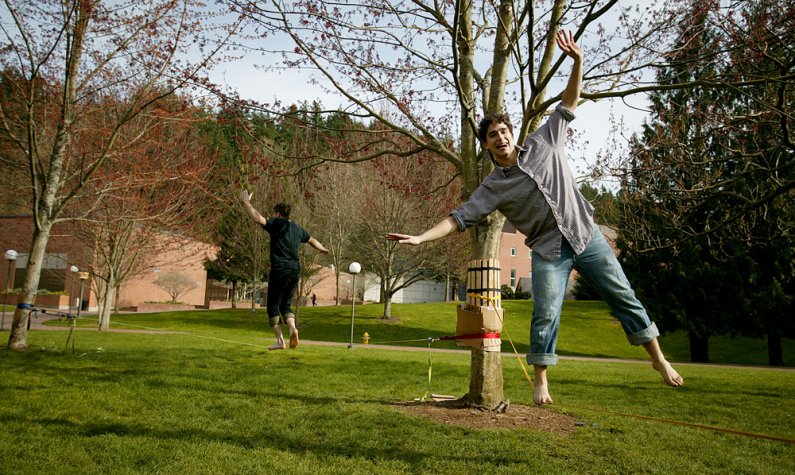Western Washington University students Frank Vitolo, right, and Cory Olson practice slacklining between three trees near Carver Gymnasium and the Science, Mathematics and Technology Education Building on campus in March. University gardener Randy Godfrey 