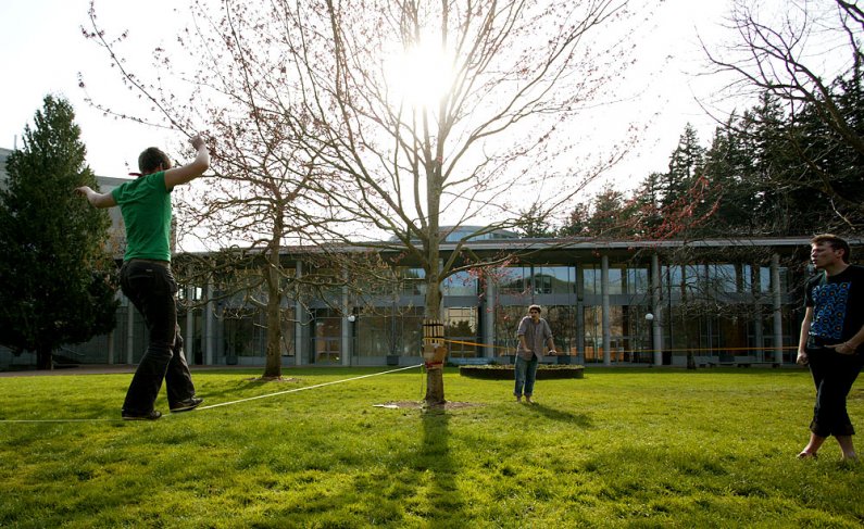 Western Washington University student Ruthie Taylor, left, practices her slacklining while friends Frank Vitolo and Cory Olson look on. University gardener Randy Godfrey recently placed protective wooden guards on a couple of trees to prevent damage. The 