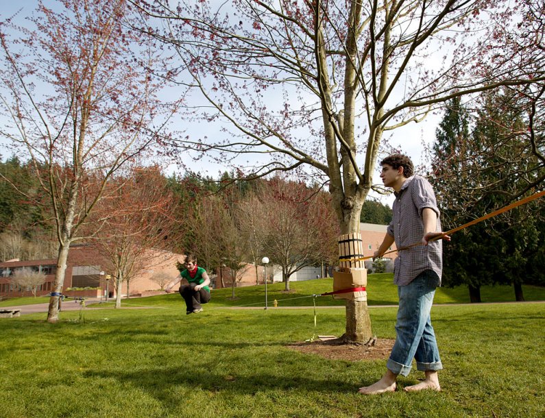 WWU music performance major Frank Vitolo rests on a slackline on the south side of Carver Gymnasium on campus while friend Ruthie Taylor balances on a different section of line. University gardener Randy Godfrey recently placed protective wooden guards on