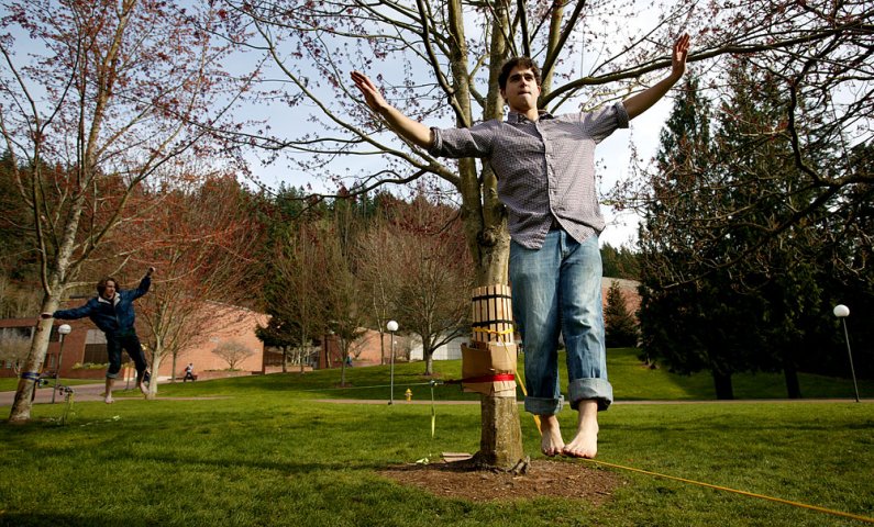 Frank Vitolo, right, a music performance major at Western Washington University, and Cameron Frazier, a WWU recreation major, practice the art of slacklining on campus Thursday, March 18.  Photo by Matthew Anderson | WWU