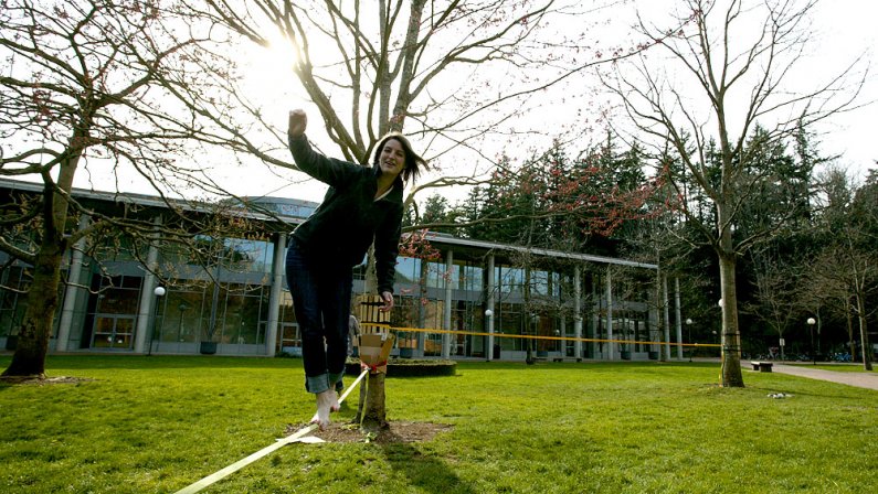 Western Washington University student Tracy Pennell walks along a slackline in front of the Science, Mathematics and Technology Education Building on campus Thursday, March 18. Photo by Matthew Anderson | WWU