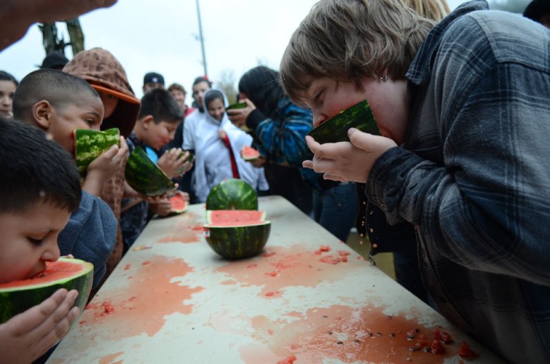 Children from the community compete in a watermelon-eating contest during the Low-in-the-360 Lowrider show in the Flag Plaza on south campus Sunday, May 15, 2011. Photo by Daniel Berman | University Communications intern