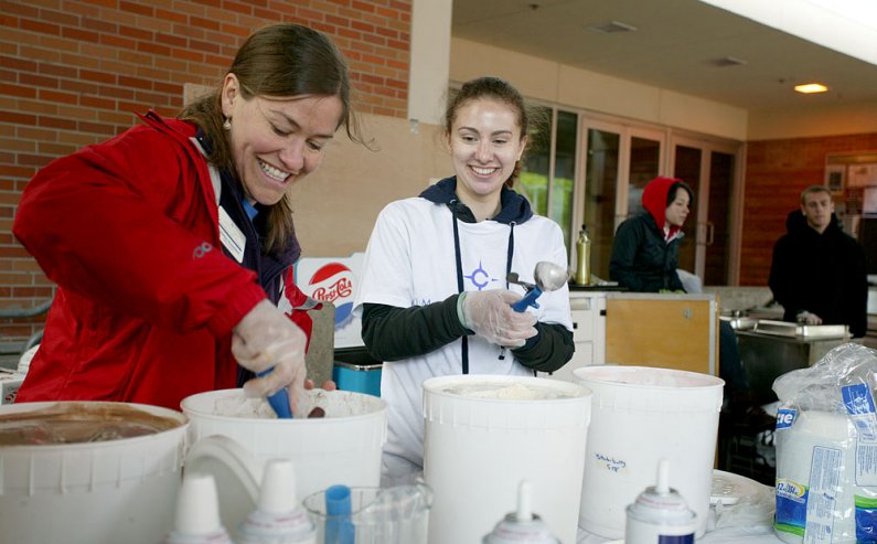 Western Washington University staff member Kristine Kunchick, left, and student Amy Denton laugh as they dish up ice cream on Vendor's Row Thursday, June 2, on the WWU campus. The ice cream was a celebration of past mentors and a publicity event for gaini