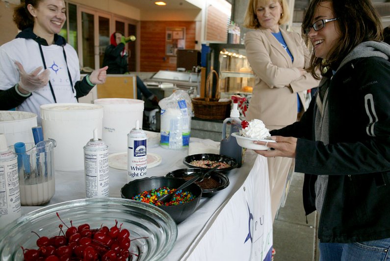 Western Washington University student Kara Braich, right, dishes up her ice cream while student Amy Denton, left, and C2C volunteer director Cyndie Shepard look on Thursday, June 2, on the WWU campus. Photo by Matthew Anderson | WWU