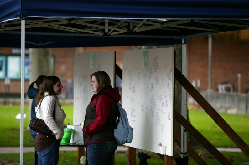 Western Washington University students Rochelle Wilkowski, left, and Amber Arnold chat near a couple of panels set up in Red Square on which community members can write their thoughts regarding the recent death of student Dwight Clark. Photo by Matthew An