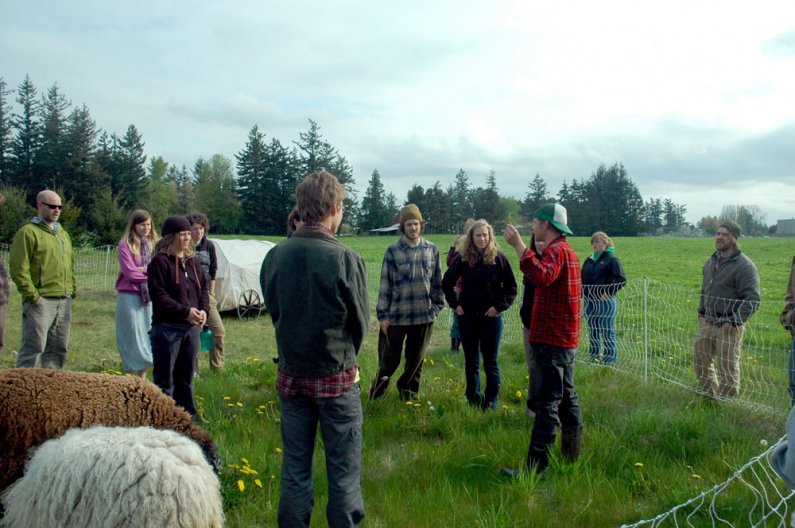 WWU alumnus Michael Long, red coat, of Growing Gardens farm in Lynden, talks to Fairhaven students about raising sheep and chickens in a rotational grazing system. Photo courtesy of John Tuxill