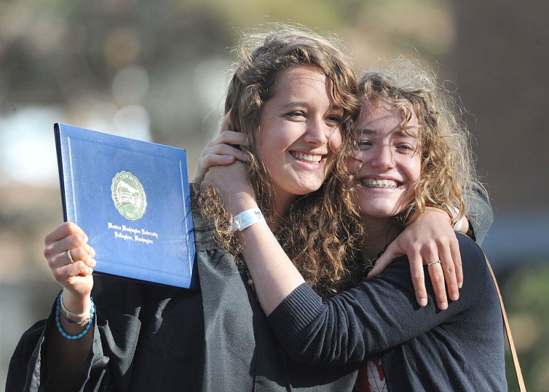 WWU graduate Meaghan McClure, left, is hugged by her sister Emma McClure as they pose for family pictures after commencement ceremonies June 11. Photo by Dan Levine | for WWU