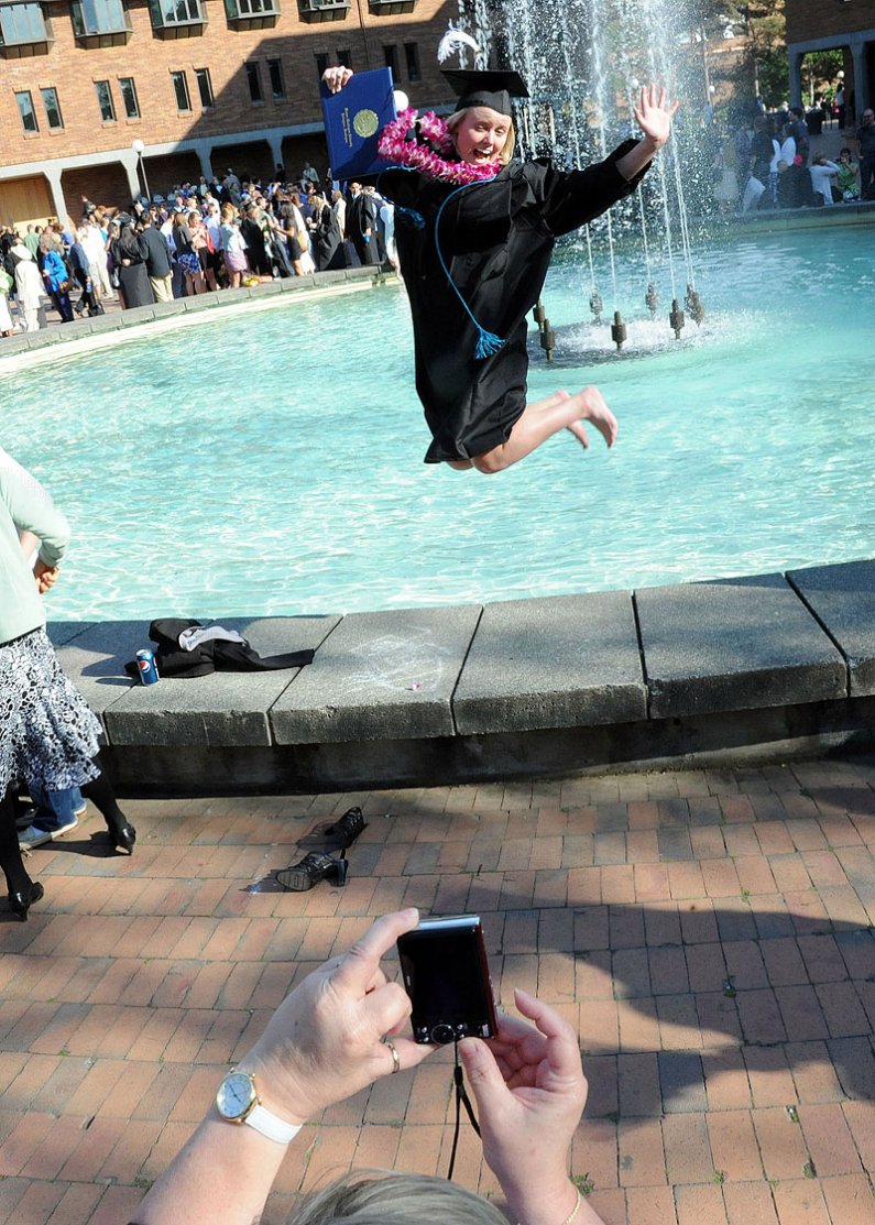 WWU graduate Kaitlin Duffy leaps for family photos after commencement ceremonies June 11, 2011, on campus.