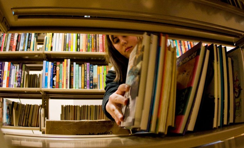 Western Washington University student Jessica Wolfer stacks books onto shelves in Wilson Library Room 171. Hundreds of new books will be on sale Thursday and Friday, Dec. 3 and 4. Photo by Jon Bergman | WWU intern