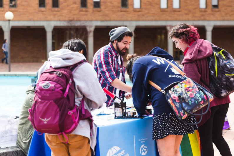 WWU student Alberto Rodriguez-Escobedo co-hosts a button-making station in Red Square promoting the Zero Waste Club and the Queer Resource Center's collaborative clothing swap on Monday, April 9.