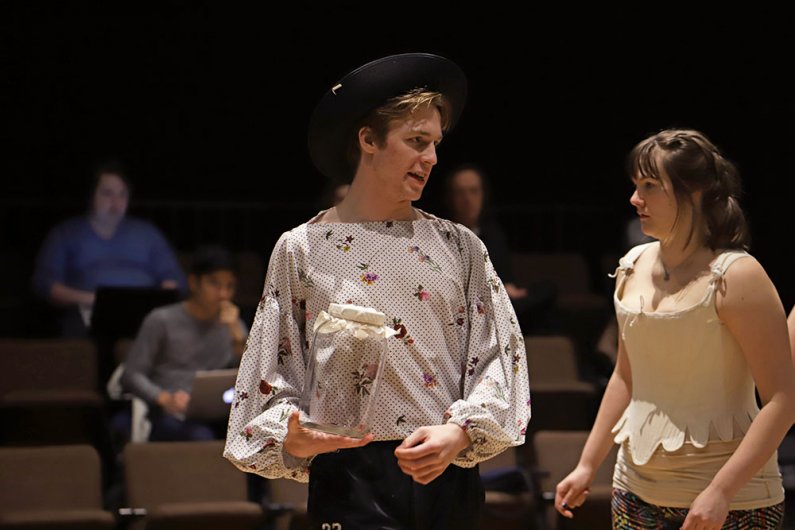 Two student actors facing towards the back of the stage in conversation 