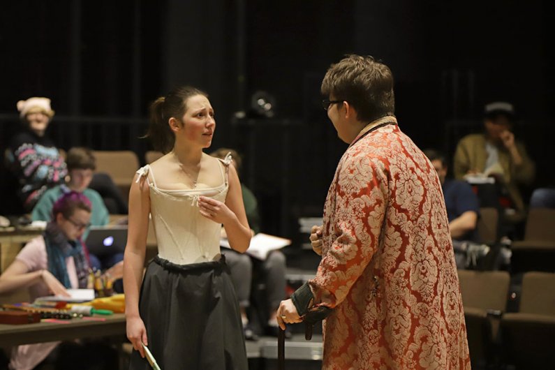 Two student actors conversing on stage