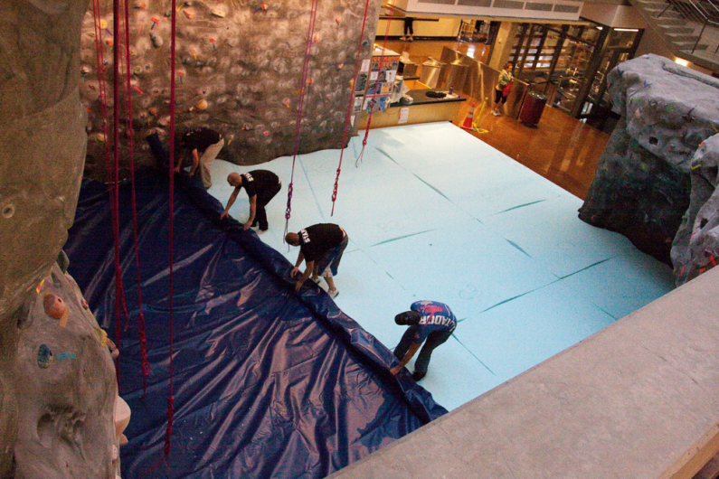 Workers roll out vinyl on top of a new padded floor under the rock wall Friday, Oct. 23, at the Wade King Student Recreation Center on campus. The original floor, which was installed in 2003, no longer provided adequate cushion for climbers. Photo by Jon 
