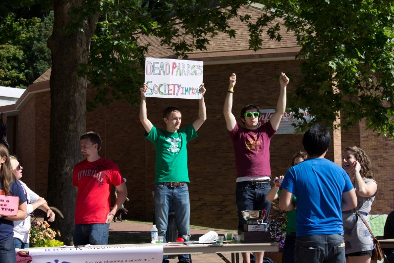 Western sophomore Greg Phelps and Western senior Miguel Vila hold up a sign for the Dead Parrots Society, an improv comedy group at Western, at the 2011 info fair on Sept. 19. Photo by Christopher Wood | University Communications intern