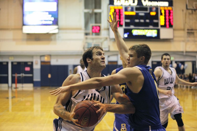 Western junior Dan Young dodges a University of Alaska Fairbanks player Thursday, Jan. 13, in Carver Gym.  The Vikings won the game with a score of 108-96, improving their record to 9-4 overall and remaining unbeaten at home. Photo by Alex Roberts | Unive