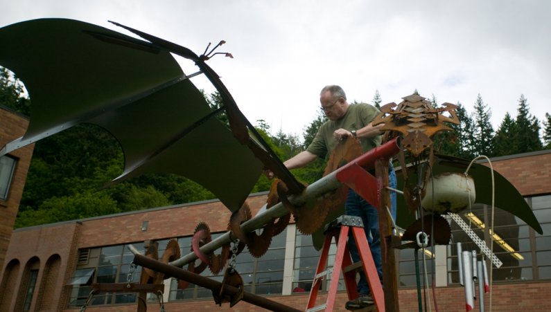 John Zylstra, a classroom support technician in the WWU Art Department, checks the strength of the welds on the recently installed dragon sculpture in front of the Fine Arts Building on campus on Wednesday, June 2. Zylstra was ensuring that the strong win