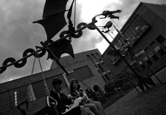 Western Washington University students Odin Ringsred, left, and Caitlyn Schumaker take a lunch break on the bench swing of a sculpture recently installed in front of the Fine Arts Building on the WWU campus. The dragon sculpture was created by students fr