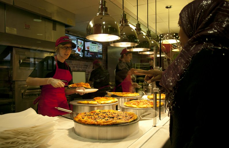 Western Washington University junior Badatu Dawud, right, receives a slice of pizza from Topio's employee Alyssa Massie, a fellow student, on Oct. 3, 2011, on the eatery's opening day. Photo by Matthew Anderson | WWU