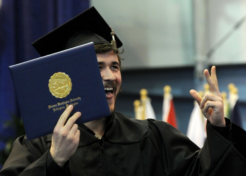 Operations Management graduate Jeremy Fox holds his diploma while flashing a smile to the crowd during commencement ceremonies in Carver Gymnasium on the Western Washington University campus March 19, 2011. Photo by Dan Levine