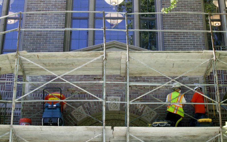 Workers remove bricks and mortar from above the northern entrance to Wilson Library on Wednesday, July 14. Photo by Matthew Anderson | University Communications
