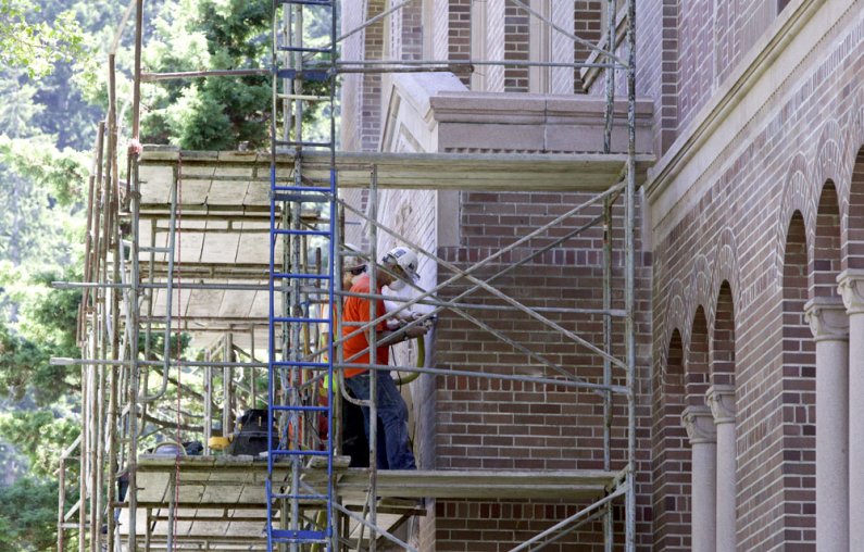Workers remove bricks and mortar from above the northern entrance to Wilson Library on Wednesday, July 14. Photo by Matthew Anderson | University Communications