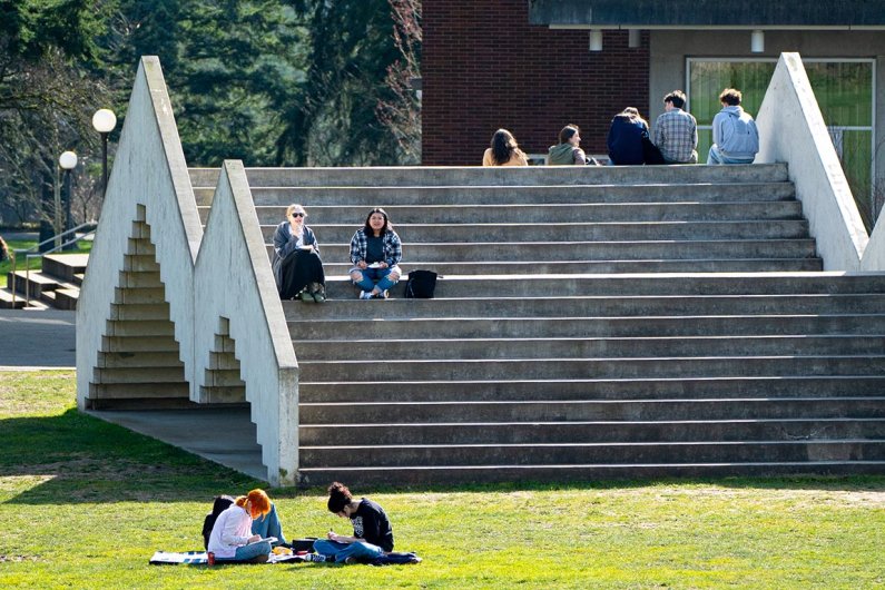 Students sit on the "stairs to nowhere" sculpture on south campus on a sunny day.