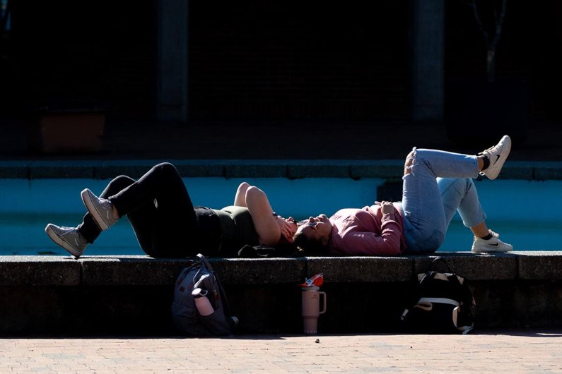 Students lie on the edge of Fisher Fountain; the fountain is empty.