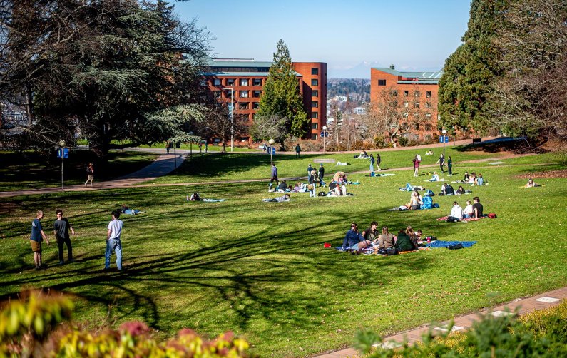 The Old Main lawn is covered in blankets and relaxing students on a warm sunny spring day.