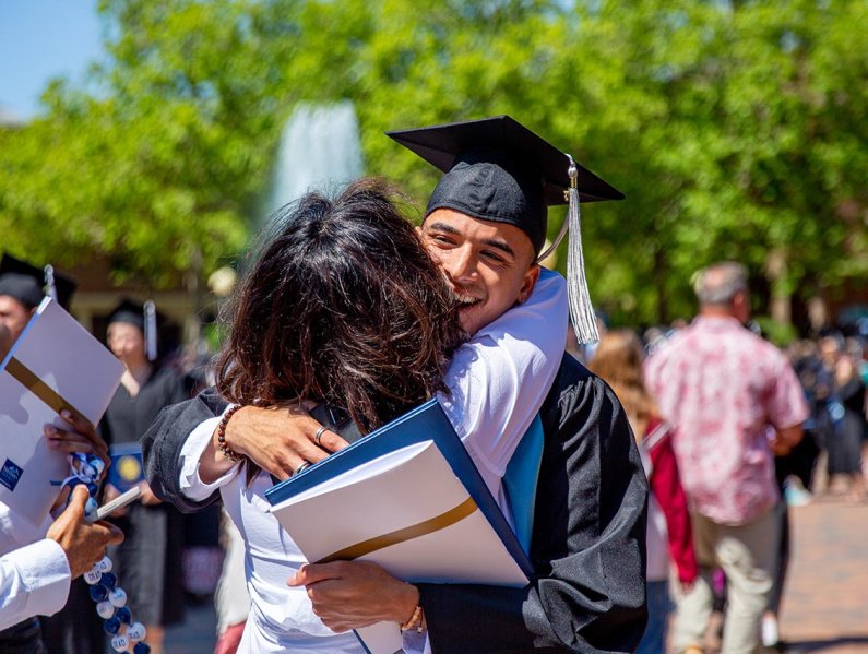 A new alumnus hugs a family member in Red Square after commencement