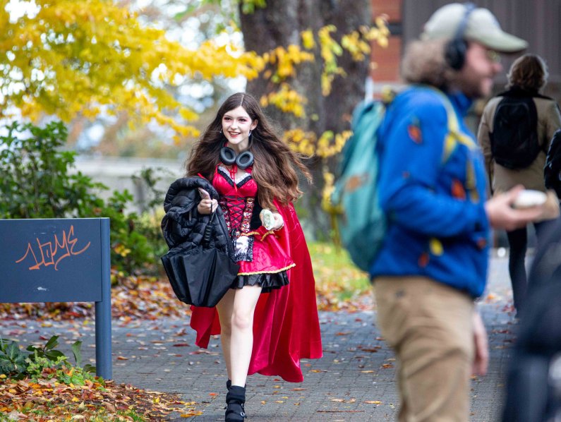 A student walks across campus in a red witch costume