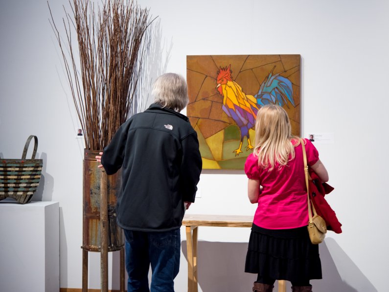 people looking at a painting of a rooster