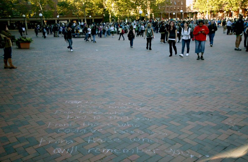Students leaving the gathering for Dwight Clark on Wednesday walk past a message written on the outskirts of Red Square. Photo by Matthew Anderson | WWU