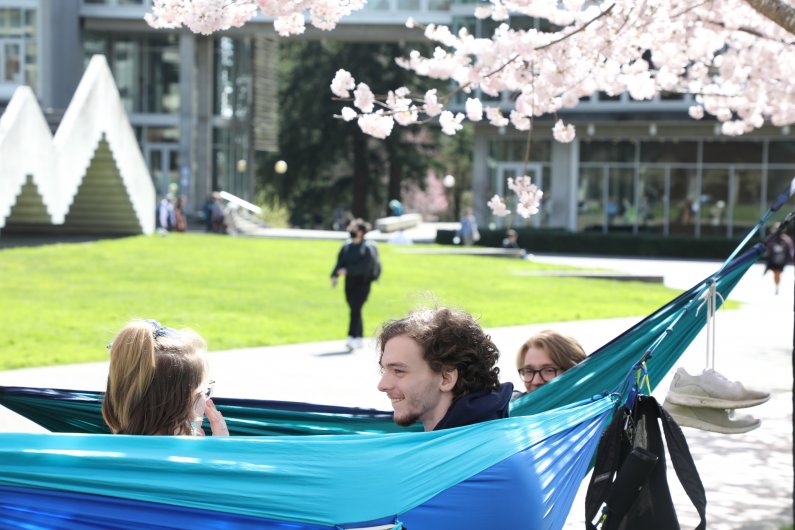 Three students hammocking on South Campus on a sunny spring day