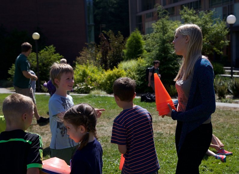 WWU senior Taylor Andrykowski helps the campers gather up cones from their relay race before going inside for free time.  Photo by Alex Bartick / WWU Communications and Marketing intern