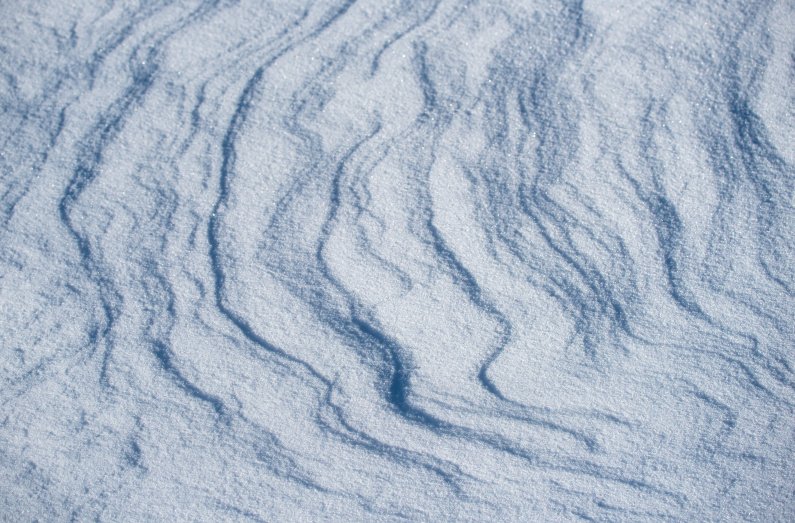 wind sculpts patterns in a snow drift on a frigid winter day on campus